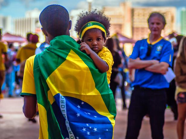 Father wrapped in Brazilian flag carrying his daughter