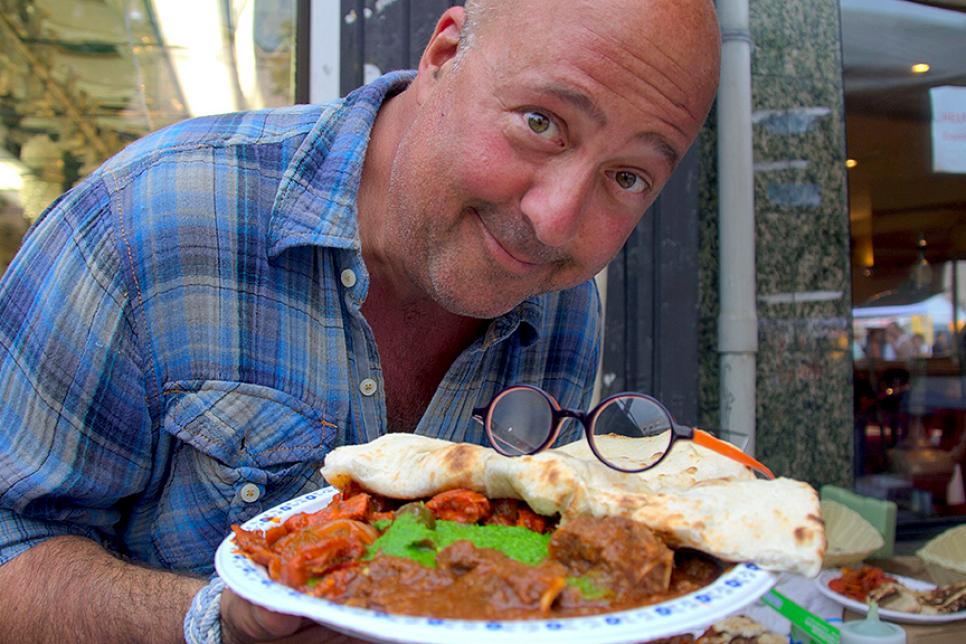 Andrew Zimmern holds a plate of goat