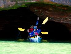 3 people kayaking, caves, cliff, river, in the shade,