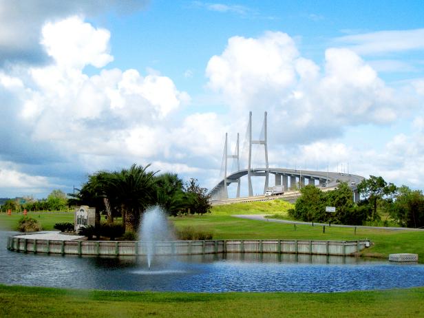 park with fountain in front of a tall bridge in background in daytime