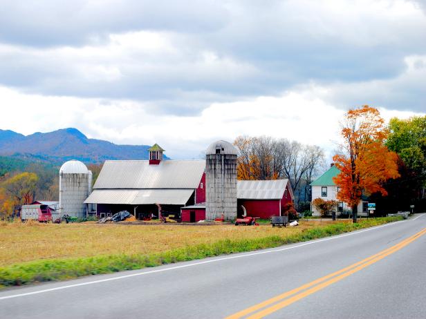 farm on left side of road during the fall with leaves changing colors and overcast sky