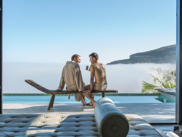 Couple having coffee on a lounge chair outside hotel room