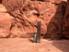 man standing next to glistening metallic structure in utah desert