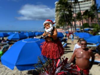 Beach goers pass by a decorated Christmas tree at Waikiki beach in Honolulu on December 25, 2013. AFP PHOTO/Jewel SAMAD        (Photo credit should read JEWEL SAMAD/AFP/Getty Images)
