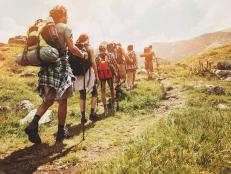 Group of hikers walking in line on a footpath in the mountain, with copy space