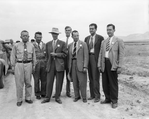 At a nuclear test site near Alamogordo, New Mexico, atomic bomb scientists measure radioactivity in seared sand particles 2 months after the explosion when newsmen saw bomb effects for the first time. Standing left to right: Dr. Kenneth.T. Bainbridge (Harvard University); Joseph G. Hoffman, (Buffalo, NY); Dr. J.R. Oppenheimer, Director of Los Alamos Atomic Bomb Project; Dr. L.H. Hempelman, (Washington University in St. Louis); Dr. R.F. Bacher (Cornell University); Dr. V.W. Weisskopf, (University of Rochester); and Dr. Richard W. Dodson (California). | Location: Near Alamogordo, New Mexico.