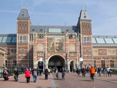 Amsterdam, Holland - April 10, 2015: Tourists and cylcists in front of the Rijksuseum with billboard of Rembrandt exhibition in Amsterdam, Holland on Apil 10, 2015