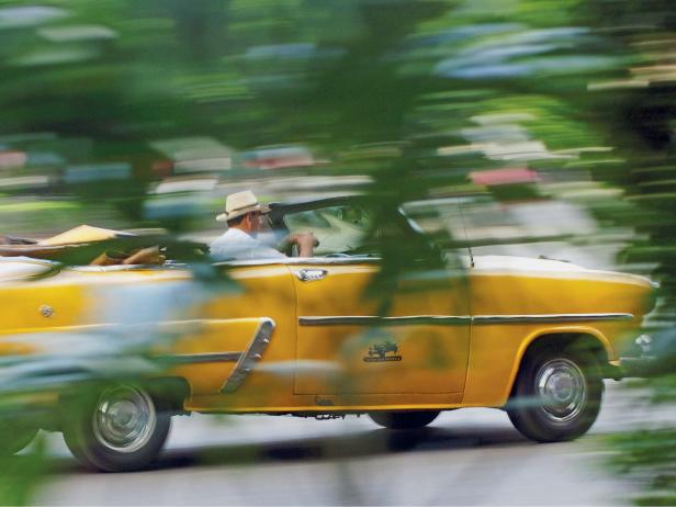 A yellow convertible speeding through the countryside in Cuba
