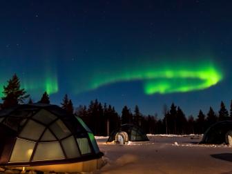 Igloo rooms in the snow with aurora overhead