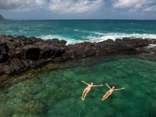 Lexi Grinpas and Chelsea Yamase floating in Queen's Bath in Princeville, Hawaii as seen on Travel Channel's Top Secret Swimming Holes episode TUSH202H.