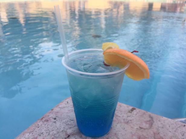 Cocktail with Orange Garnish Next to Pool