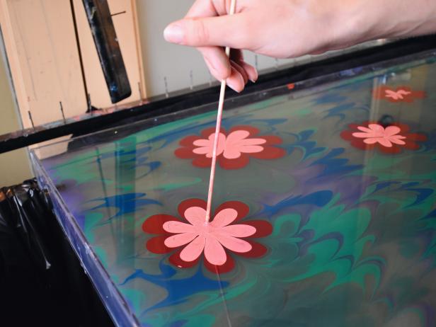 Close Up of Pigment Floating on Water With Hand Drawing a Flower