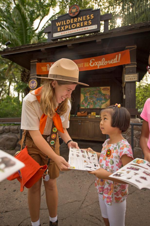 Wilderness Explorer Guide Handing Book to Little Girl