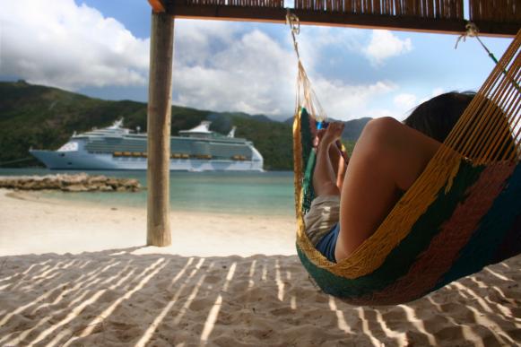  'A woman relaxes on a hammock on the beach in front of a large cruise ship
iStockphoto. Feb. 2008'