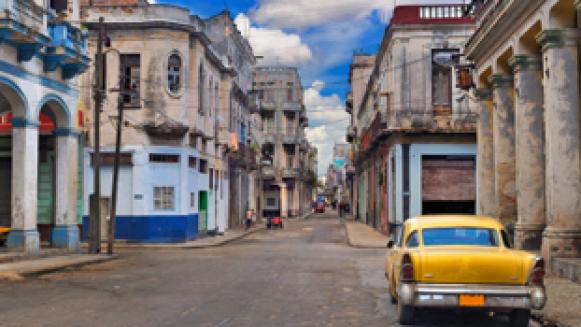  'Panoramic view of Havana street with crumbling buildings and old classic car'