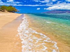 A beautiful sunny beach with crystal clear waters in Maui, HI.