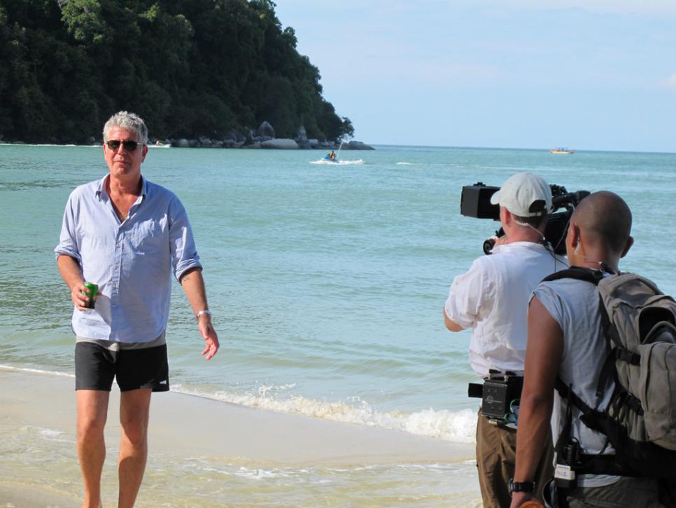 Anthony Bourdain walks on the beach on Monkey Island