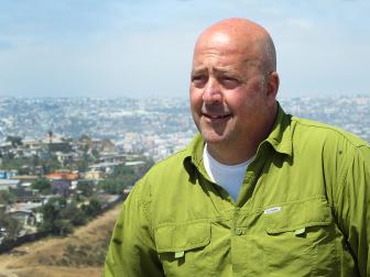  'Host Andrew Zimmern sits and overlooks the US/Mexico Border.'