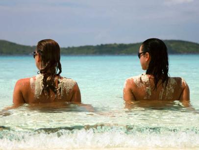 Topless ladies surrounded by dressed men at the beach