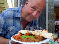 Andrew Zimmern holds a plate of goat
