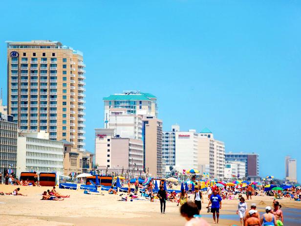 busy scene on a beach with tourists and buildings on the left during the daytime