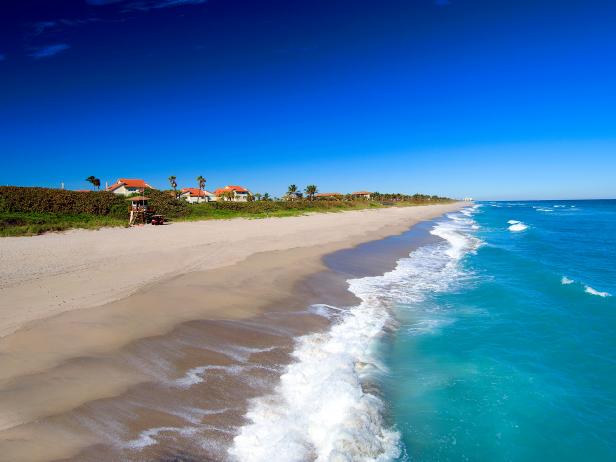 empty beach during the day in florida with houses on the left past dunes