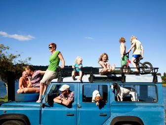 family hangs out in parked blue van during the day, shot from outside of car