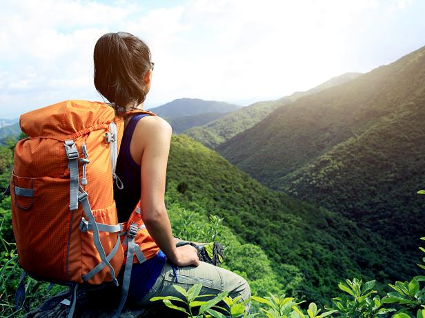 young woman standing on top of mountain overlooking various mountains