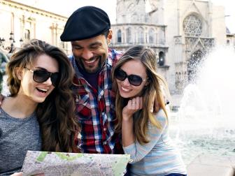 young adults smiling, looking at map with fountain behind them