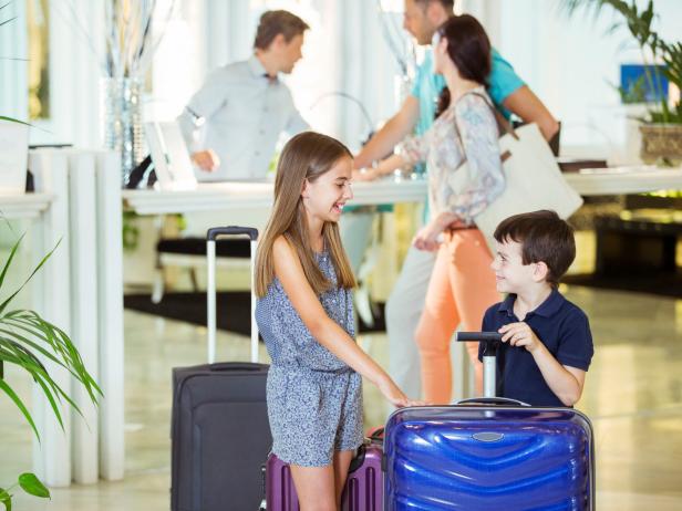 Family with daughter and son standing with suitcases in hotel lobby