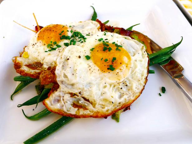 close up off fried eggs with chives and green beans white plate