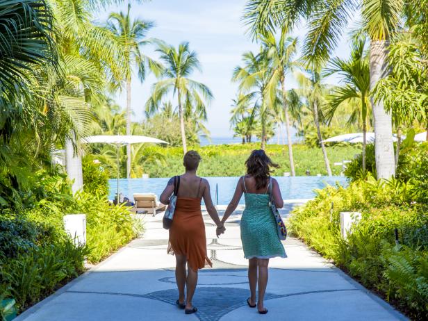 Lesbian couple holding hands at a tropical resort