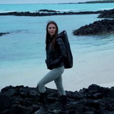Host Kinga Philipps stands on lava rock by the beach in the Galapagos, as seen on Travel Channel's Lost in the Wild.