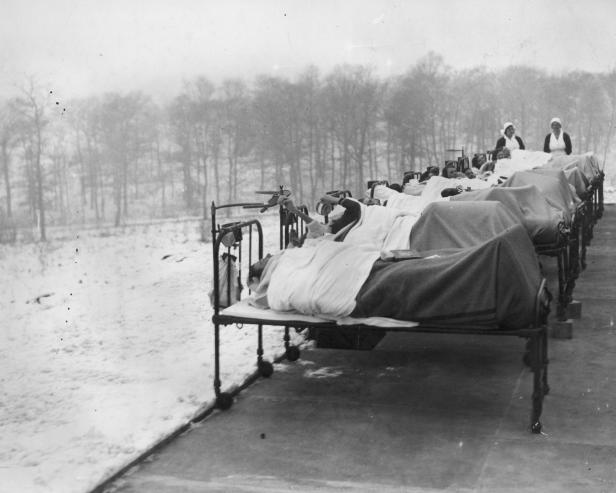24th January 1933: Patients crippled by tuberculosis are treated outdoors in the snow at the Harlow Wood Orthopaedic Hospital in Nottinghamshire. Whatever the weather, they spend their days lying on iron bedsteads in the open air, as a 'curative' measure. [Photo by Harry Shepherd/Fox Photos/Getty Images]