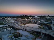 Aerial shot of downtown Tacoma, including the East 21st Street Bridge, the Tacoma Dome and the Thea Foss Waterway. In the distance, Mt Rainier looms against the colorful sunset.