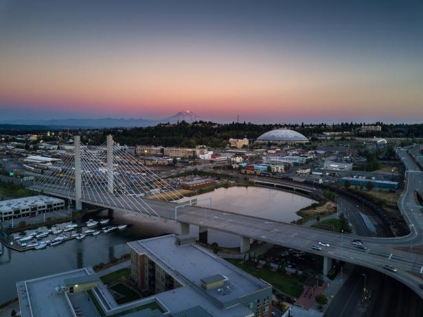 Aerial shot of downtown Tacoma, including the East 21st Street Bridge, the Tacoma Dome and the Thea Foss Waterway. In the distance, Mt Rainier looms against the colorful sunset.