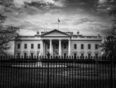 Black and white image of the United States presidential residence with flag on roof in the nations capital