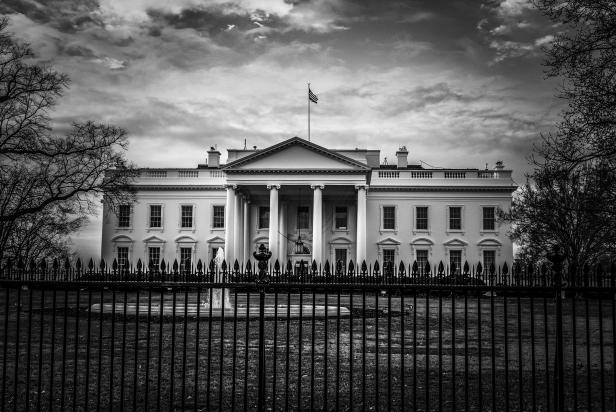 Black and white image of the United States presidential residence with flag on roof in the nations capital