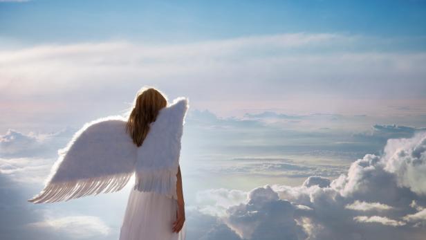 Woman with angel wings standing over clouds in the blue sunny sky