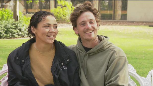 Lateche Norris (left) and her boyfriend, Joseph “Joey” Smith (right). Sitting in front of a green grass background, Lateche looks at her Joey smiling wearing a black jacket and a tan top. Joey smiles wearing a green sweatshirt.