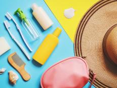 Summer travel accessories flat lay photography. Straw hat, cosmetic bag and toiletries kit