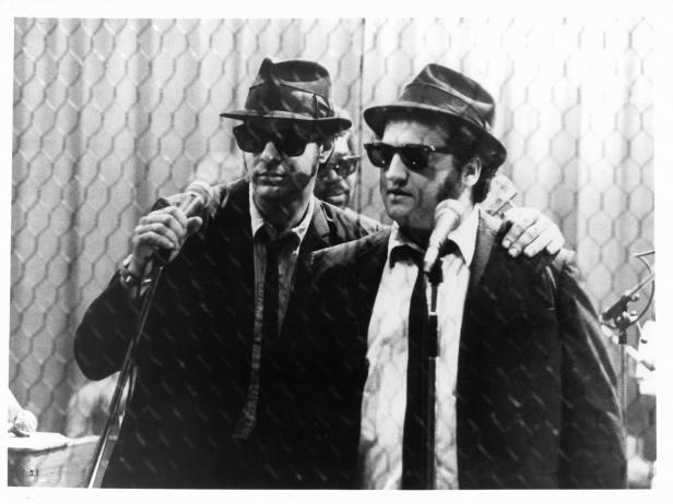 Dan Aykroyd holds a microphone standing next to John Belushi in a scene from the film 'The Blues Brothers', 1980. (Photo by Universal Pictures/Getty Images)