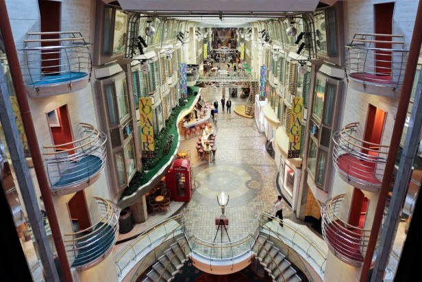 People walk through the "Royal Promenade" aboard the Royal Caribbean Cruises Ltd.'s Voyager of the Seas, berthed at the Ohi wharf in Tokyo, Japan, on Saturday, Sept. 14, 2013. Royal Caribbean, the worlds second-largest cruise-line operator, doubled its dividend and will make directors stand for election every year. Photographer: Yuriko Nakao/Bloomberg via Getty Images