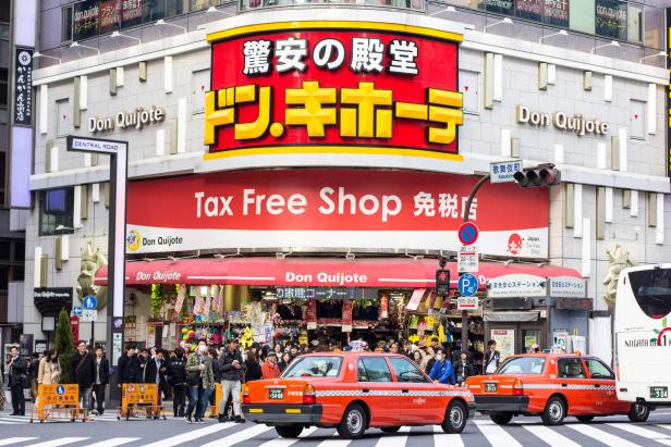 Tokyo, Japan - March 27, 2016: Pedestrians and taxis outside the Don Quijote Tax Free Shop in the commercial district of Tokyo, Shinjuku. There are several logos, names and brands on the building.