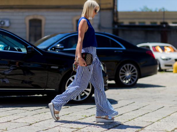 MILAN, ITALY - JUNE 20: A guest wearing a blue top, Gucci bag, silver platforms and white blue striped pants outside Gucci during the Milan Men's Fashion Week Spring/Summer 2017 on June 20, 2016 in Milan, Italy. (Photo by Christian Vierig/Getty Images)