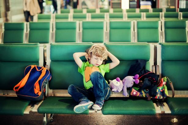 Young boy waiting at airport boarding hour.