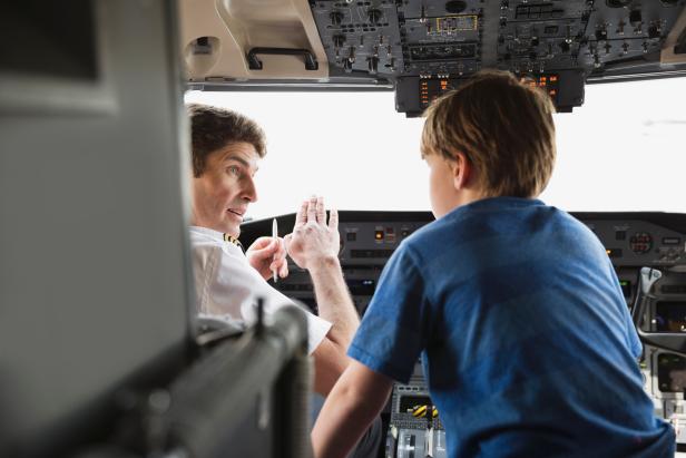 Male pilot explaining control panel to boy in airplane cockpit