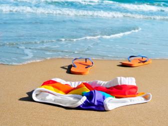 rainbow swimsuit and orange flip-flops in the sand of a beach