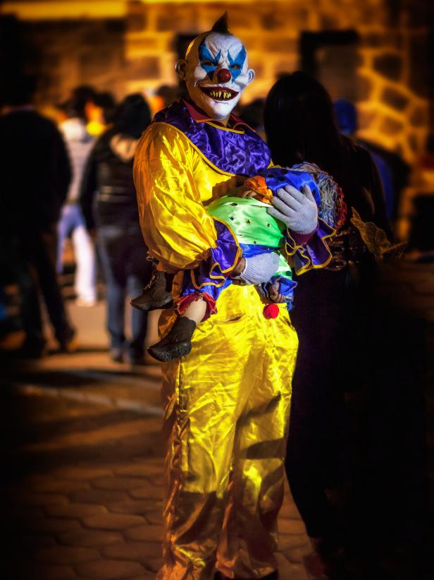 spooky clown in the street carring a child in day of the dead, mexico