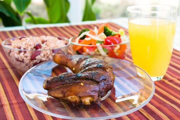 "Barbecued chicken leg also known as Jerk Chicken - Caribbean style served with vegetables, rice and lemonade.  Shallow DOF."